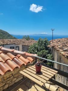 a wooden bench on a balcony with a view of the ocean at Villa Olive Old Qeparo in Qeparo