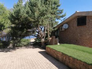 Villetta dei Ginepri في كوستا باراديسو: منزل من الطوب مع شجرة وجدار من الطوب