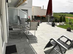 a patio with chairs and tables and an umbrella at Ferienwohnung mit herrlicher Aussicht "Ihre Urlaubs-Oase auf Zeit!" in Bad Dürrheim