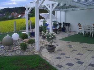 a patio with a white pergola and some plants at Ferienwohnung mit herrlicher Aussicht "Ihre Urlaubs-Oase auf Zeit!" in Bad Dürrheim