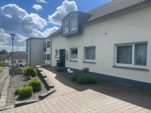 a white house with a brick driveway at Ferienwohnung Eifelliebe in Bitburg