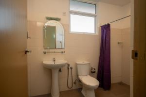 a bathroom with a toilet and a sink and a mirror at Hotel Oviya in Vavuniya