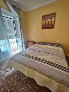a bedroom with a bed with a painting on the wall at Apartamento corrales in Chipiona