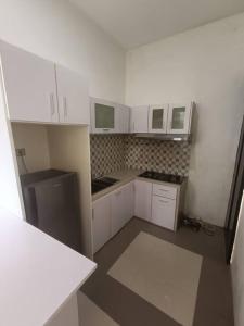 a small kitchen with white cabinets and appliances at Rumah Besar dg Kolam Ikan diKota in Kebumen