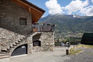 a stone building with a balcony with flowers on it at Maison Bebe Terre Blanche in Aosta