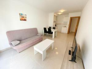 a living room with a couch and a table at Apartamentos Playa de la Lanzada 3000 in Revolta