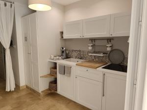 a white kitchen with white cabinets and a sink at La Petite perle, balnéo en supplément, le Clos des Perles in Tourtour