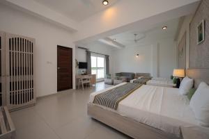 a large white bedroom with a large bed and a desk at Hotel Oviya in Vavuniya