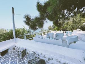 a white balcony with white chairs and tables on a hill at La Casa del Nespolo - Exclusive Country Suites - Seaview Pool & Self Check-in in Capo dʼOrlando