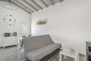 Una sala de estar con un sofá y un reloj en la pared. en Casa El Trebol, en Vejer de la Frontera