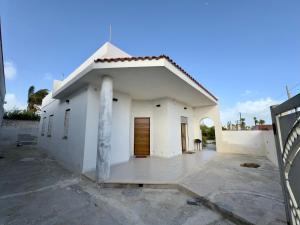 a white building with a door in a parking lot at Villa Franca on sea in Mazara del Vallo