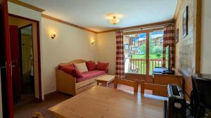 a living room with a red couch and a window at Résidence Les Alpages 4 étoiles - Appartement 4 personnes - Piscine, Hammam, Sauna, Jacuzzi - ValCenis 73480 in Lanslebourg-Mont-Cenis