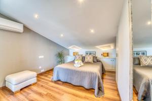 een zolderslaapkamer met twee bedden en een stoel bij Ideal Property Mallorca - Xiscama in Alcudia +56 foto's