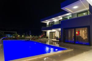 a blue swimming pool in front of a house at night at VILLA PAOLA in Polača
