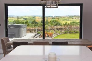 a dining room with a view of the countryside through a window at Stylish home with HOT TUB in St Merryn +21 photos