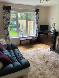 a living room with a black leather couch in front of a window at Blacklion Holiday Homes in Blacklion
