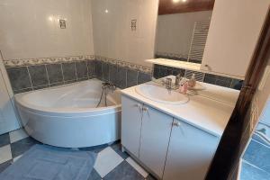 a bathroom with a tub and a sink and a bath tub at Grand gite 12 personnes proche du Lioran in Thiézac