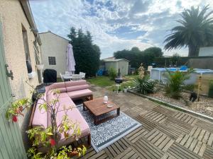 a patio with a pink couch and a wooden table at Roxy House in Le Château-dʼOléron +4 photos