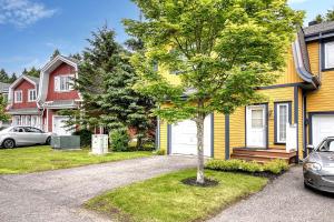 een geel huis met een auto op de oprit bij 146 Borealis - Close to the Mountains in Mont-Tremblant in Mont-Tremblant