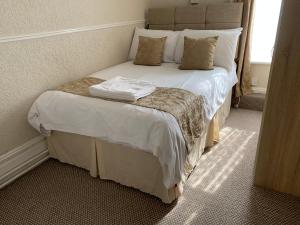 a bedroom with a bed with white sheets and pillows at Sharn Bek Hotel in Blackpool