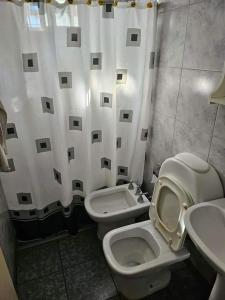 a bathroom with a toilet and a sink and a shower curtain at Refugio El Condor in Balneario El Condor
