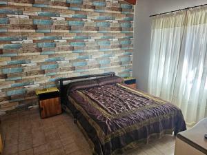 a bedroom with a brick wall and a bed at Refugio El Condor in Balneario El Condor +7 photos