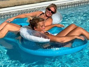 two women are riding on an inner tube in a swimming pool at Blue Mountains Bed and Breakfast in Blue Mountains