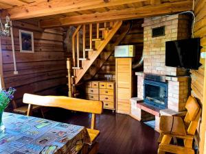a living room with a table and a fireplace in a cabin at Sodyba pas Juozą in Milkai