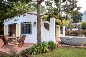 a patio with a table and a tree at Cape Weaver cottage in Greyton