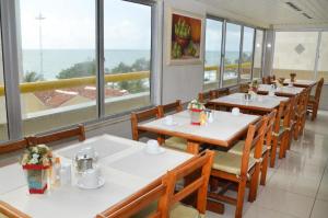 a dining room with tables and chairs and windows at Villa Mar Boa Viagem in Recife +50 photos