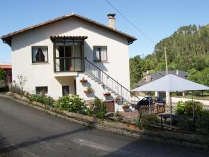 a white house with a table and an umbrella at Casa con patio en Nueva de Llanes - El Churru in Nueva de Llanes
