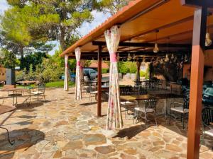a pavilion with tables and chairs on a stone patio at Bungalow GOLOSINA in Torrelaguna