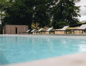 Una piscina con una fila de sillas al lado. en BANDIAT Le Domaine, en Fargeas 14 fotos más