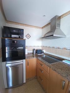 a kitchen with a stove and a microwave at Apartamento Duquesa de España Torremolinos in Torremolinos +24 photos