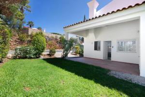 a backyard of a white house with a green lawn at Villa Lynn - Quadradinhos in Almancil