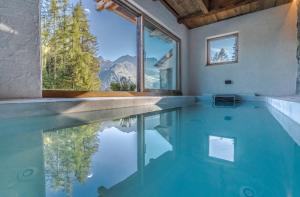 a swimming pool with a view of the mountains at Chalet Dolomites Luxe con Spa, Piscine, Jacuzzi e Cinema Privato in Livinallongo del Col di Lana