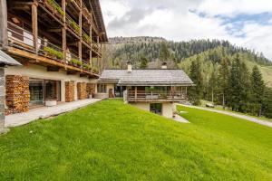 a house with a green lawn next to a building at Chalet Dolomites Luxe con Spa, Piscine, Jacuzzi e Cinema Privato in Livinallongo del Col di Lana