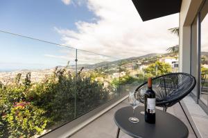 a table with a wine bottle and two glasses on a balcony at The View Flat in Funchal