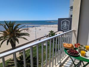 een tafel met een bord eten op een balkon met uitzicht op het strand bij Sol-y-Days le Royal Grand studio centre ville vue mer avec parking in Le Grau-du-Roi