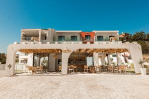 a white building with chairs and tables on a beach at Acron Suites in Limenaria