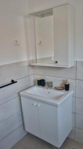 a white bathroom with a sink and white cabinets at Zelena oaza in Krk