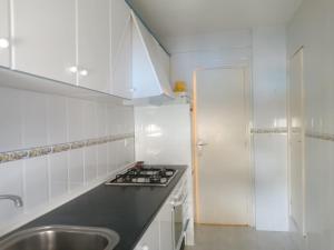 Una cocina blanca con fregadero y estufa. en Apartamento acogedor en playa Gandía, en Playa de Gandía