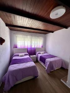 two beds in a room with purple sheets at House Beach in Bolonia
