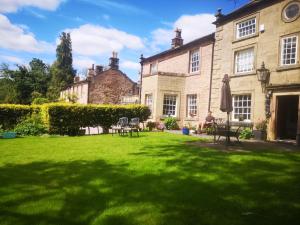 a yard with chairs and an umbrella in front of a building at Rock House Attic in Bakewell