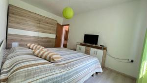 a bedroom with a bed with striped sheets and a television at Cozy Apartment Koper - New 2023 in Pobegi