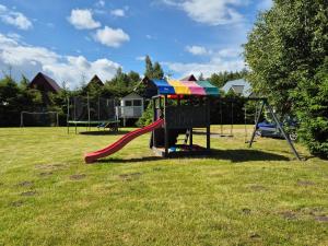 a playground with a slide in the grass at Domki Letniskowe Bryza in Jarosławiec