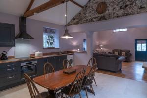 une cuisine et une salle à manger avec une table et des chaises en bois dans l'établissement Kingfisher Cottage Upperdale Peak District, à Buxton