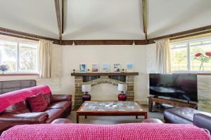 een woonkamer met een bank en een tv bij Grade II Old Engine House, on the SW Coast Path in Noss Mayo