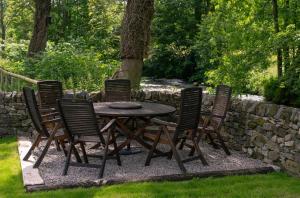 une table et des chaises en bois dans une cour dans l'établissement Kingfisher Cottage Upperdale Peak District, à Buxton 2 autres photos