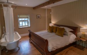 une chambre avec un lit, une baignoire et un lavabo dans l'établissement Kingfisher Cottage Upperdale Peak District, à Buxton